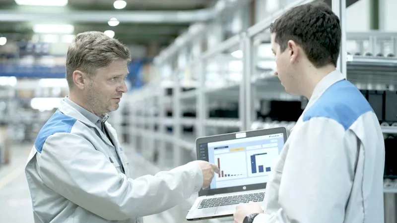 Ein Produktions-Manager und ein Produktionsingenieur stehen in der Produktion und diskutuieren die Kennzahlen im Shopfloor Management