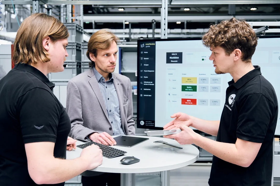 Shopfloor Management Meeting mit drei Teilnehmern in der Produktion.