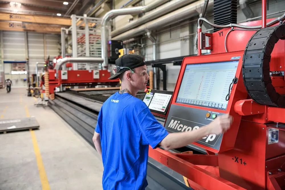 Ein junger Arbeiter steht an der automatisierten Schweißanlage von Lindner