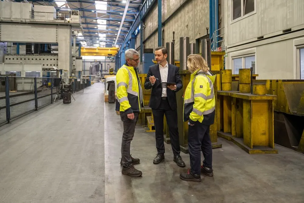 Benjamin Grünauer, Geschäftsführer bei Siempelkamp, steht mit zwei Mitarbeitenden auf dem Shopfloor